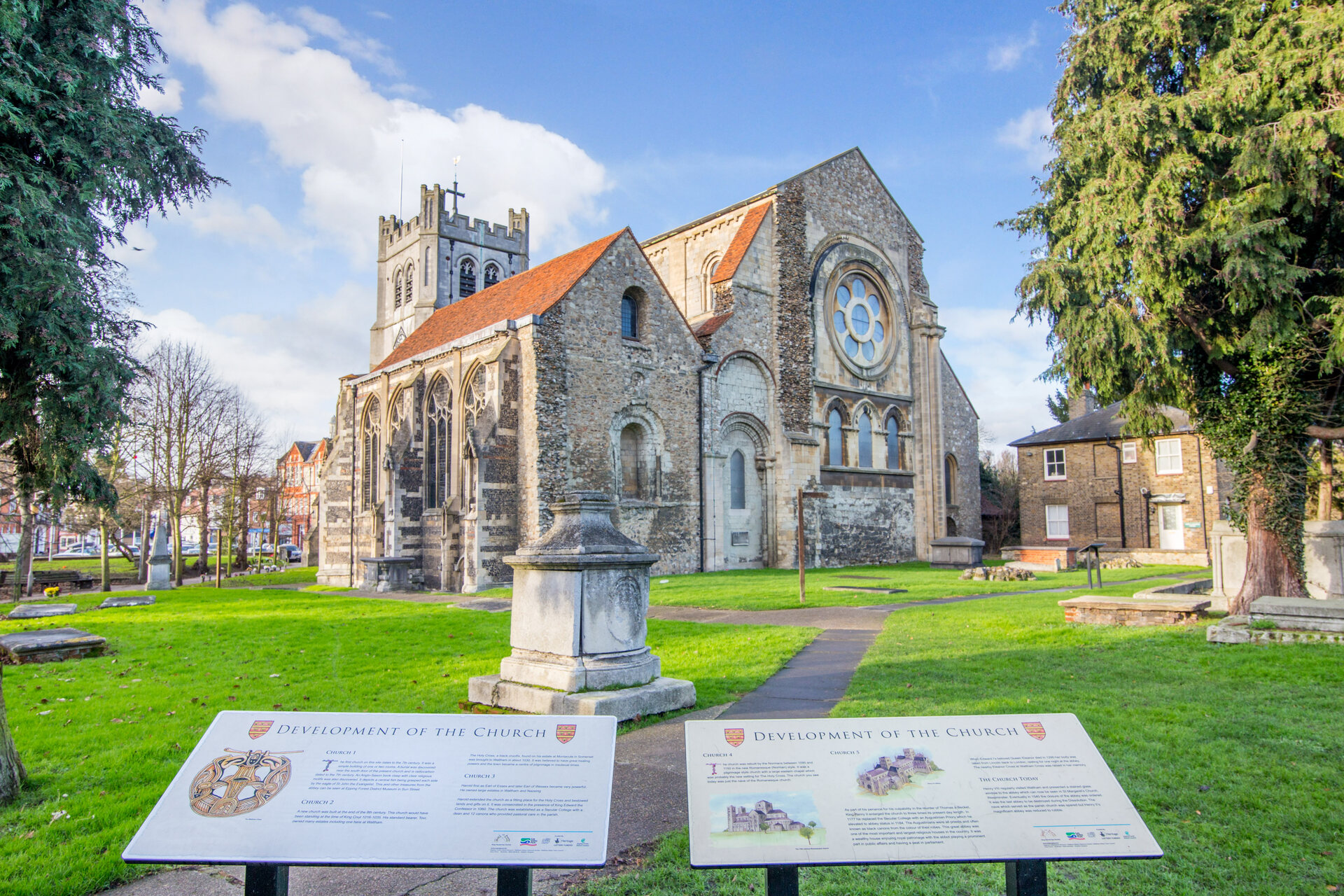 Waltham abbey on a lovely day, with information signs in foreground.